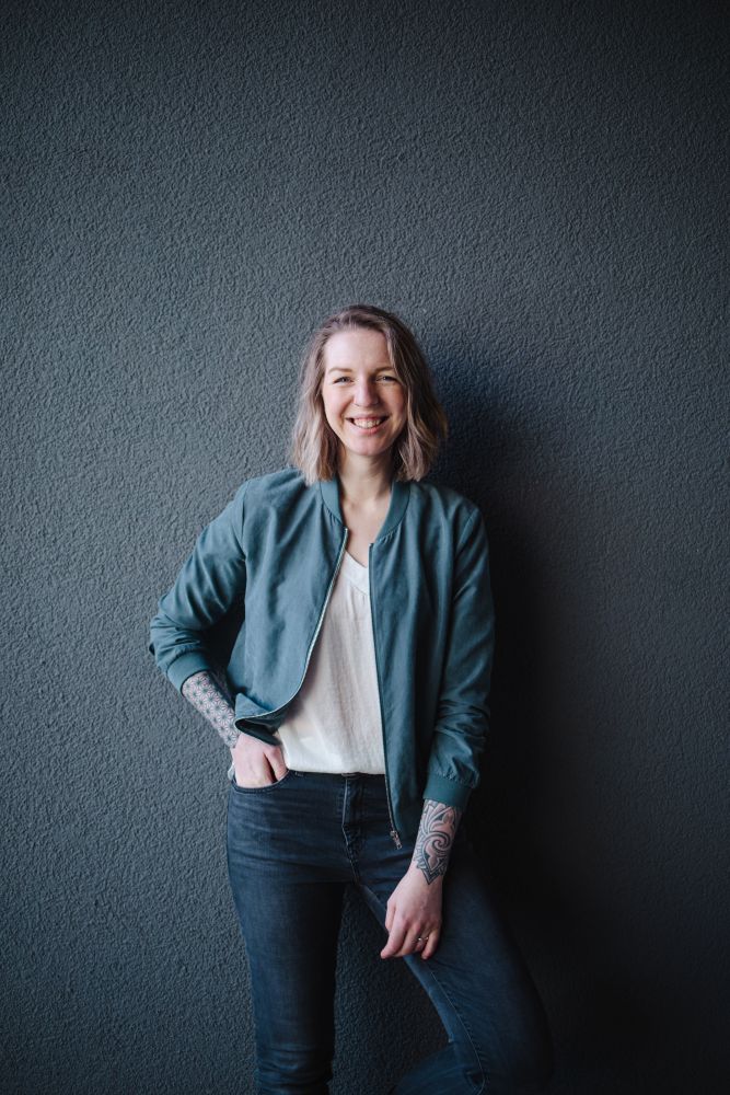 Portrait von Texterin Luisa Häußer in legerer Kleidung vor dunklem Hintergrund